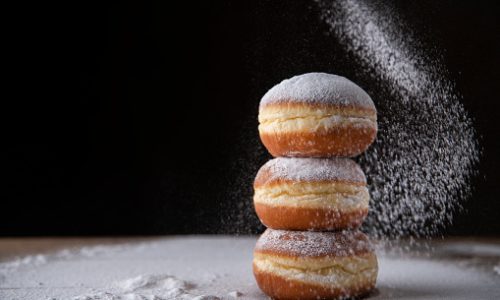 Three donuts filled with marmelade sprinkled with powdered sugar. Traditional Mardi Gras or Fat Tuesday doughnut.